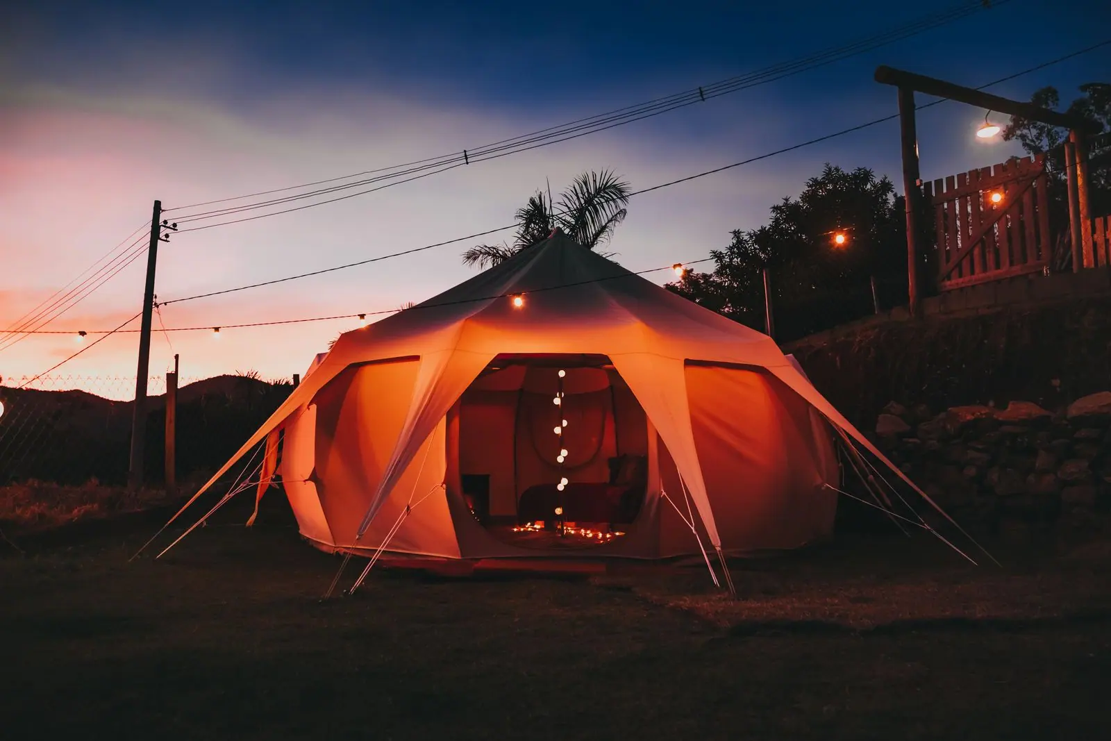 Warm string lights hanging inside a canvas bell tent.