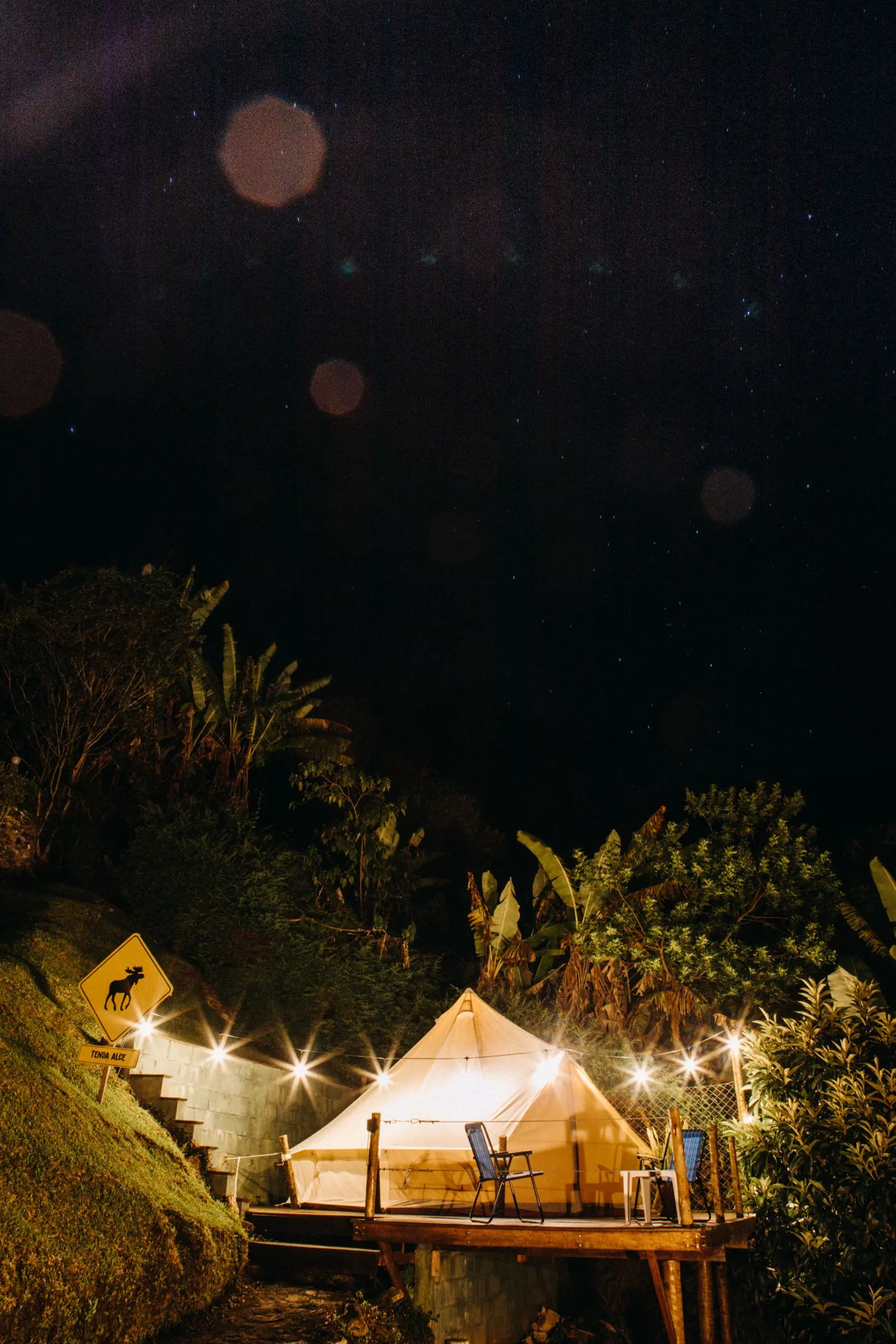 A large canvas tent lit by string lights, open toward the night.